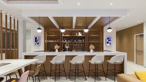 Une cuisine moderne dotée d’un îlot central, de tabourets de bar et d’un coin repas avec une table et des chaises blanches.
