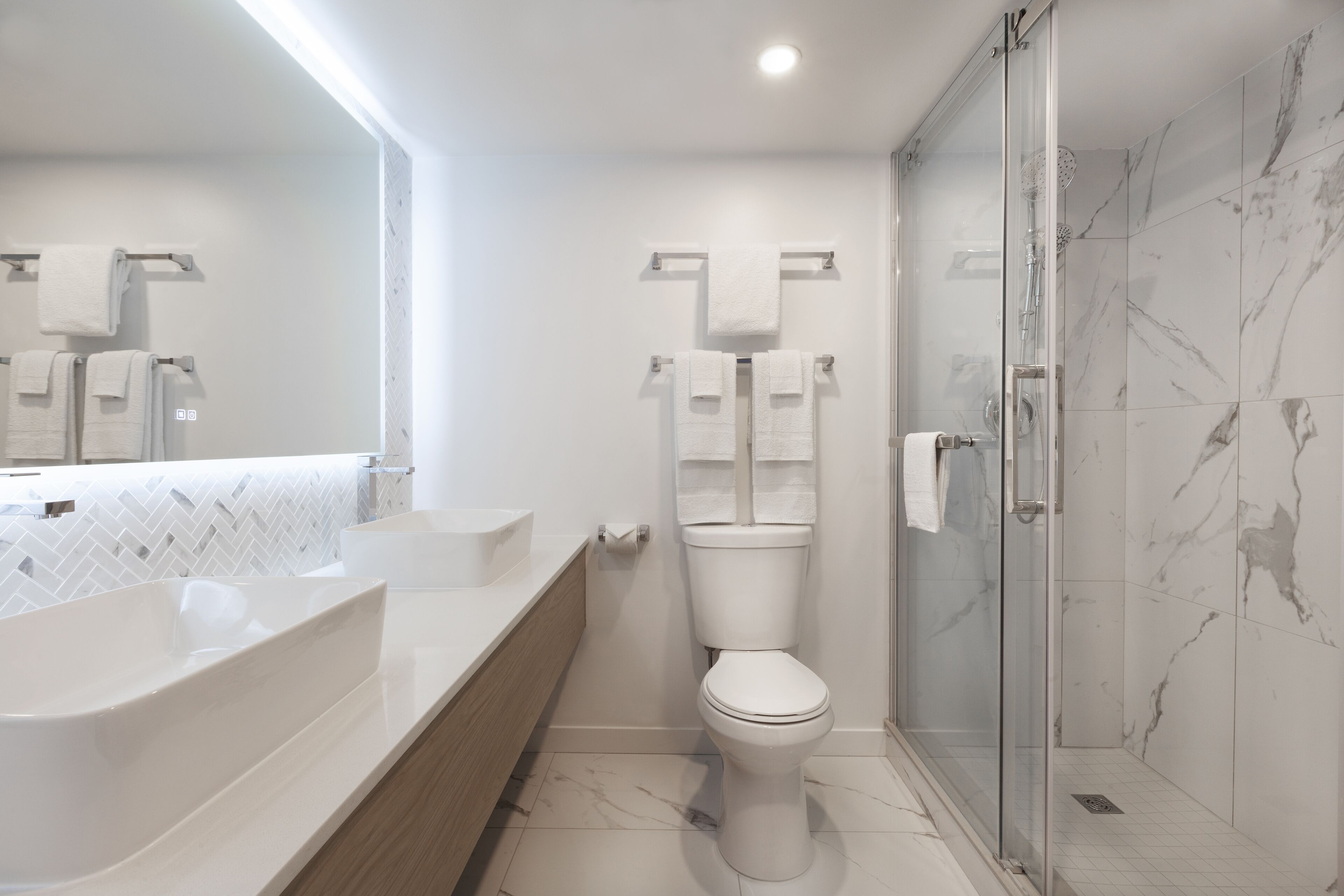A modern bathroom with a large white sink, a toilet, and a glass shower enclosure.