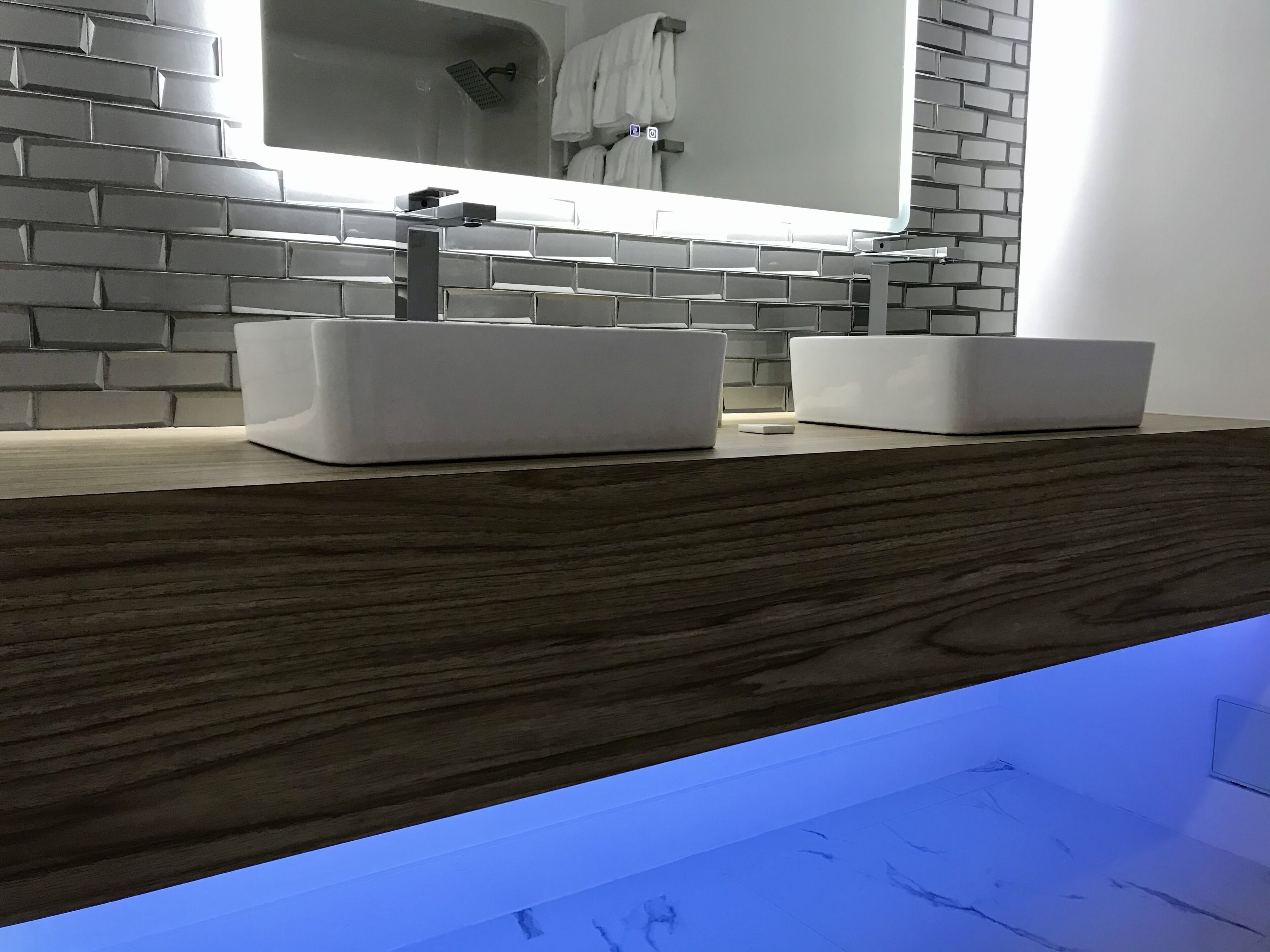 Une salle de bain moderne avec un lavabo blanc, un miroir et un plan de travail en bois.