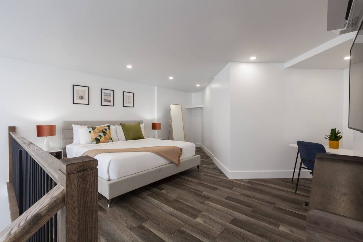 A modern bedroom with a large bed, a desk, and a chair.