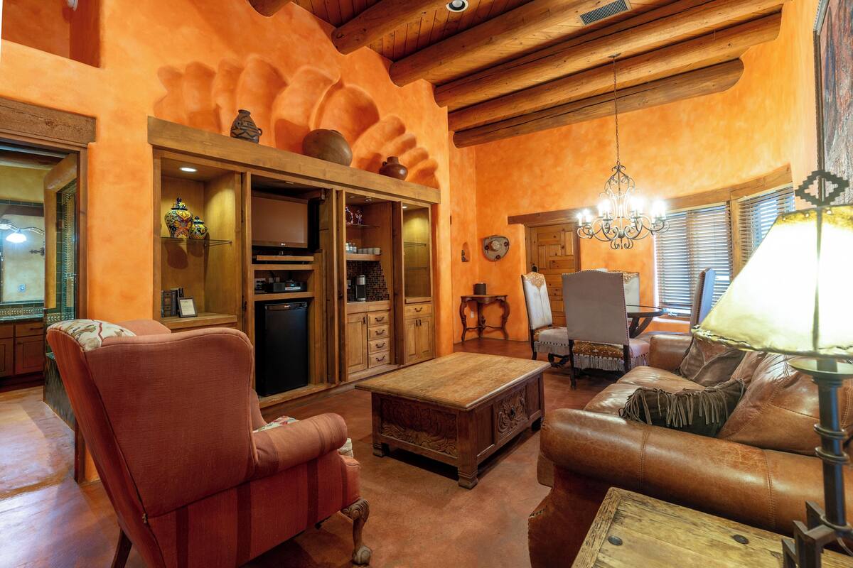 A cozy living room with a wooden coffee table, leather sofa, and a red armchair.
