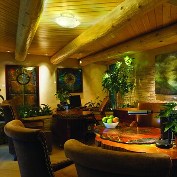 A cozy dining area with wooden furniture, a stone wall, and various potted plants.