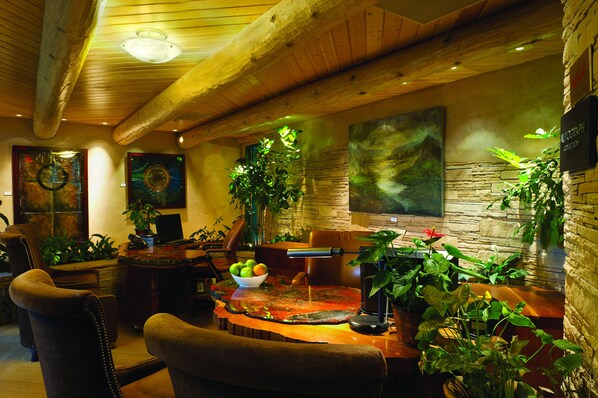 A cozy dining area with wooden furniture, a stone wall, and various potted plants.