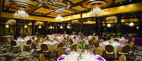 Un salón de banquetes con mesas redondas, sillas y candelabros.