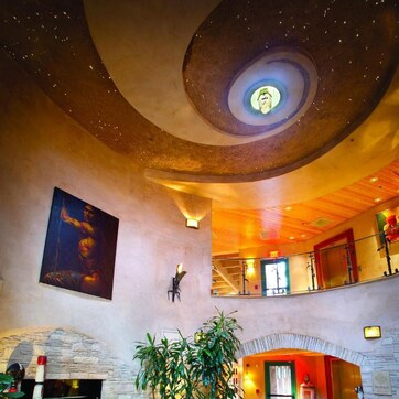 A spacious lobby with a fireplace, seating area, and a unique ceiling design.