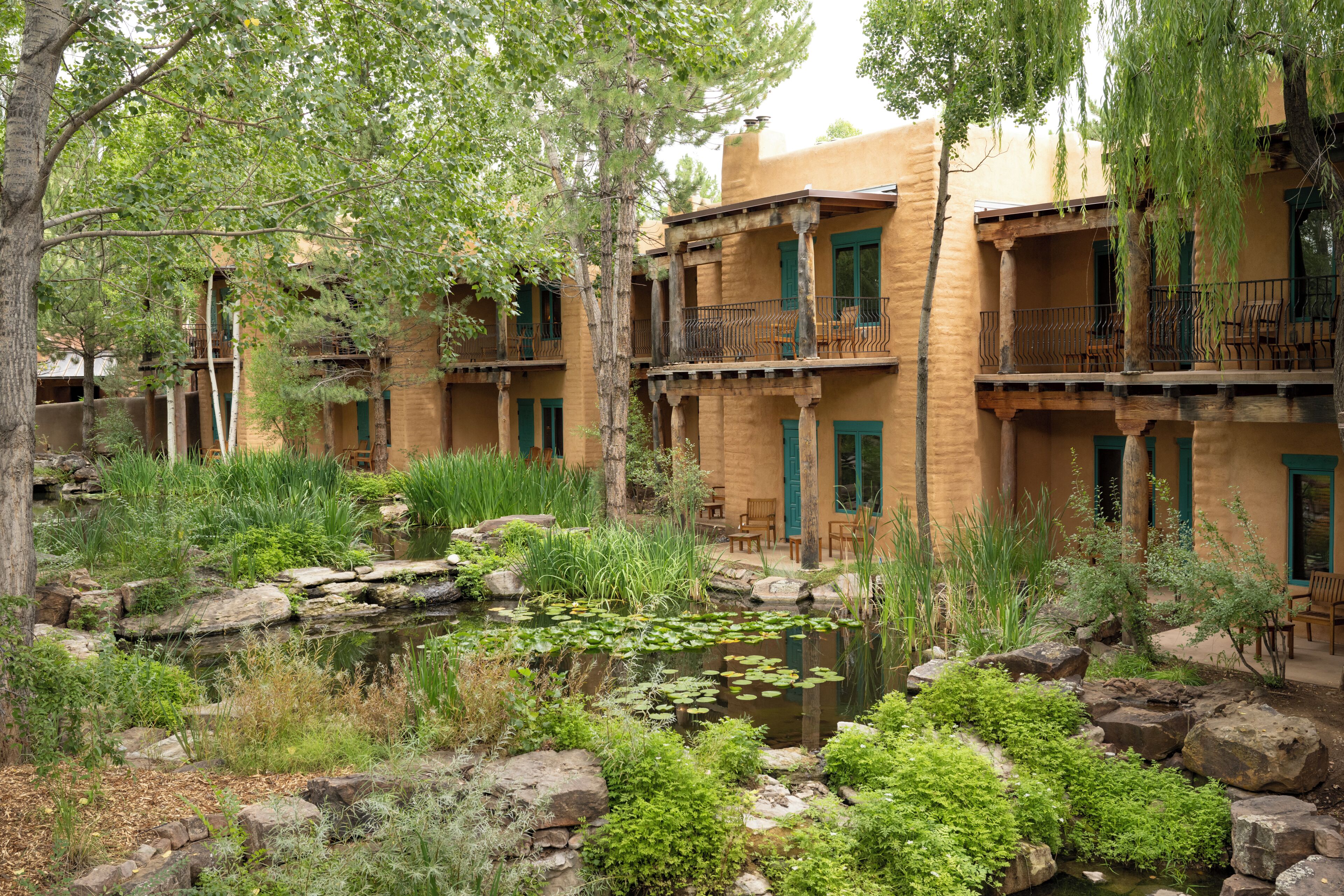 A courtyard with a pond, surrounded by multi-story buildings with balconies and outdoor seating.