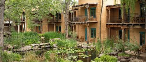 A courtyard with a pond, surrounded by multi-story buildings with balconies and outdoor seating.