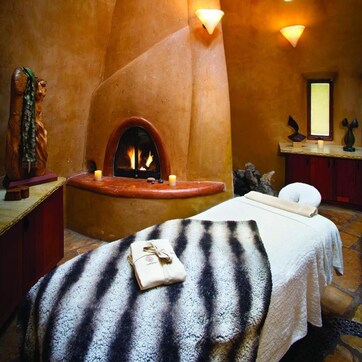 A spa room with a fireplace, a massage table, and hanging pendant lights.