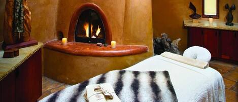 Ein Spa-Raum mit Kamin, Massageliege und hängenden Pendelleuchten.