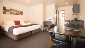 A hotel room with a bed, a dining table, and a kitchenette. - Parklands Motorlodge (Turangi)