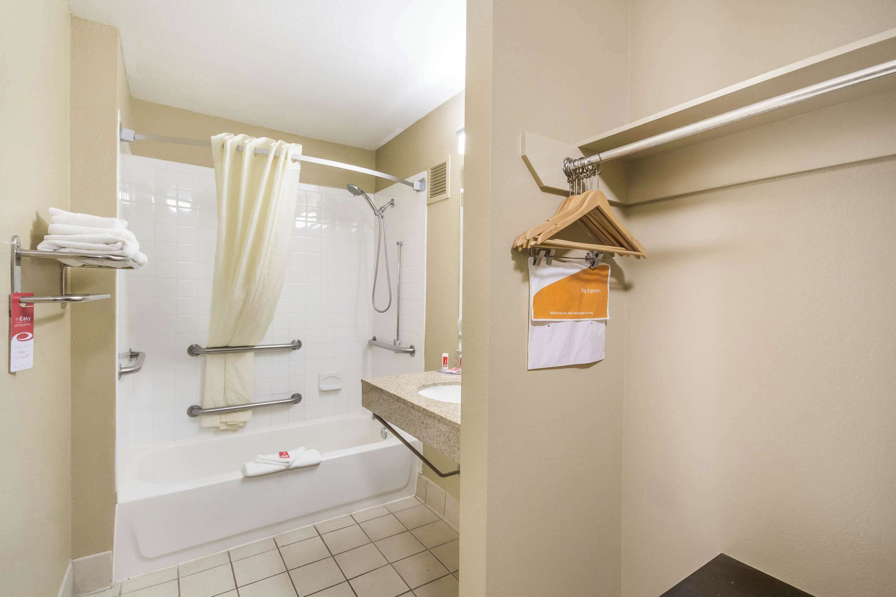 A bathroom with a bathtub, a shower, and a sink. There are towels on a shelf and a hanging rack.