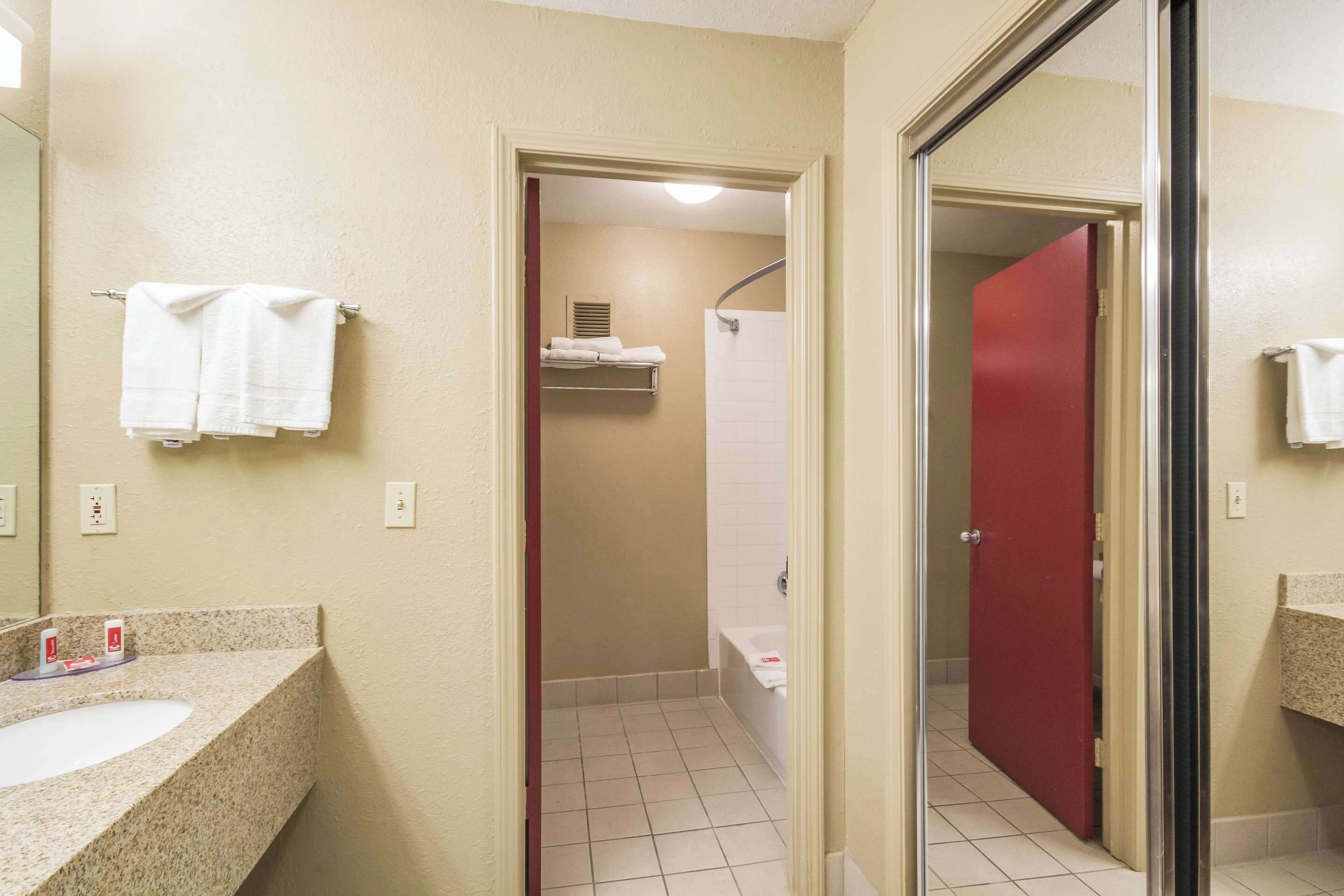Ein Badezimmer mit Waschbecken, Spiegel, Handtuchhalter, Dusche und Toilette.