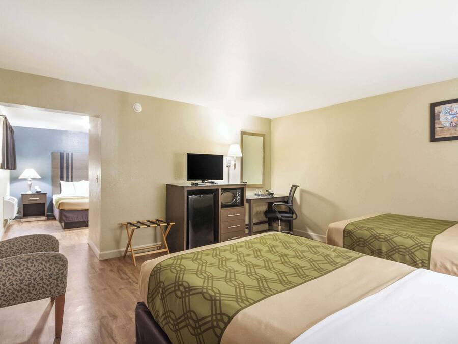 A hotel room with two beds, a desk with a computer, a TV, and a chair.