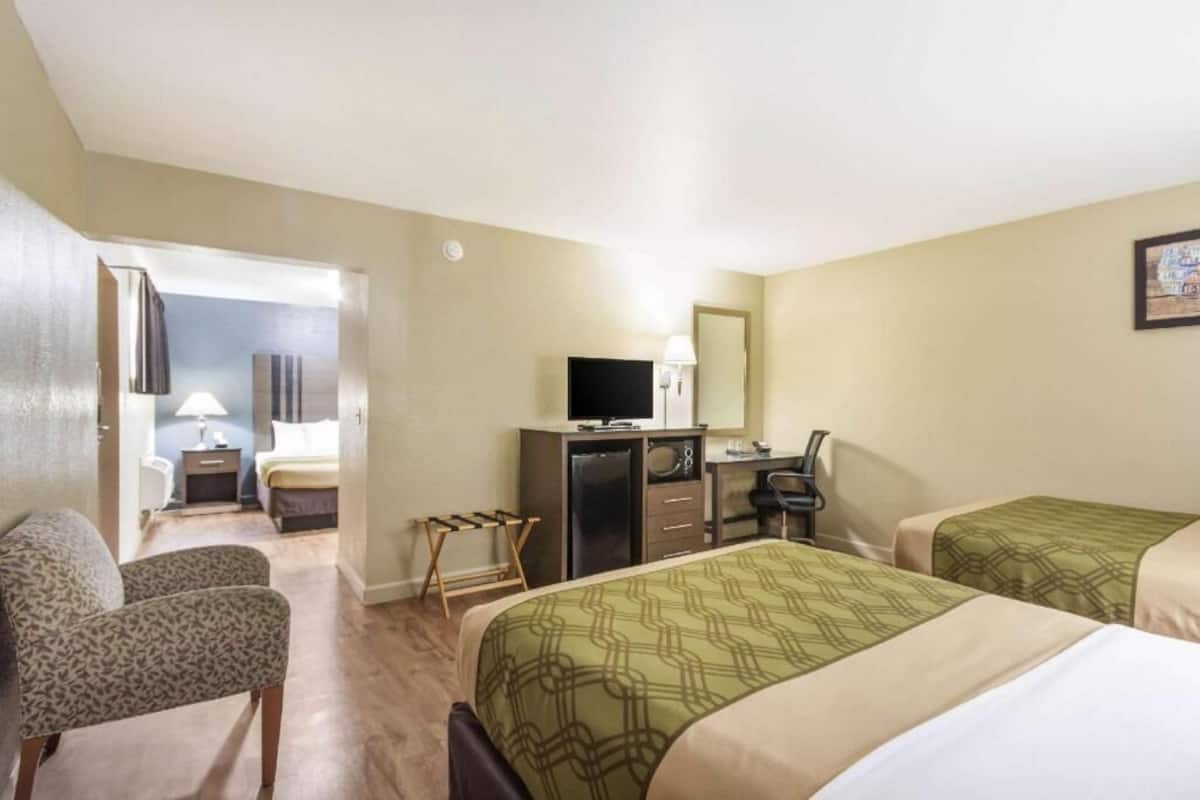 A hotel room with two beds, a desk with a computer, a television, and a chair.