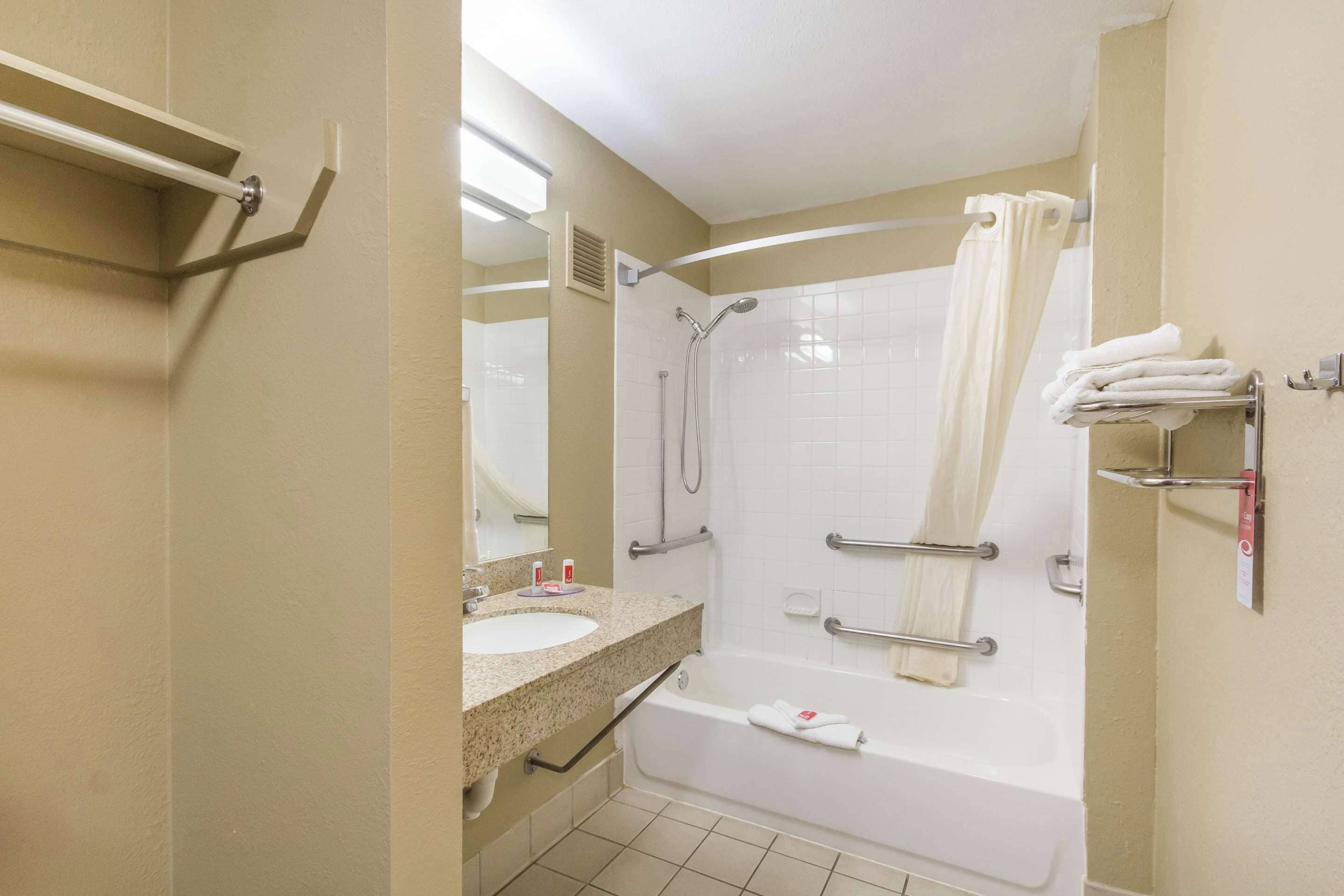 A bathroom with a sink, mirror, shower, and towel rack.