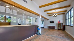 A reception area with a wooden ceiling, a reception desk, a decorative sculpture, and a large window.