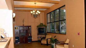 A spacious living area with a wooden ceiling, a chandelier, a television, and comfortable seating.