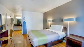 A modern hotel room with a bed, bedside tables, a desk, and a chair.