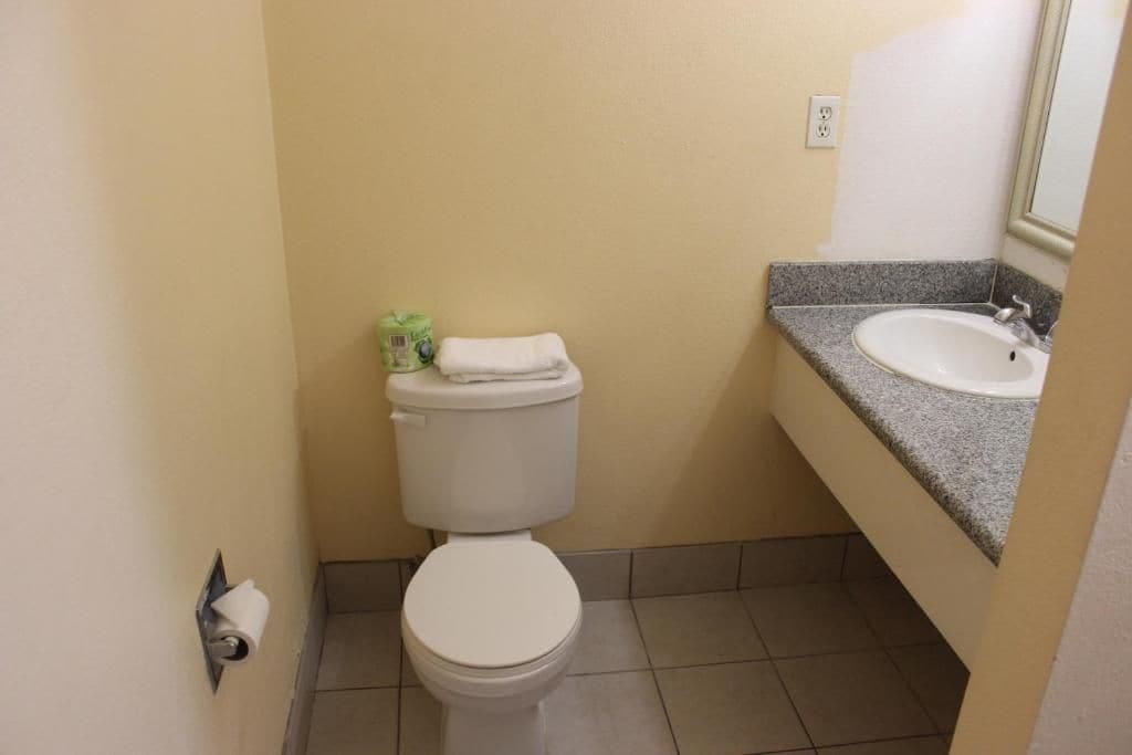 A small bathroom with a toilet, a sink, and a mirror.