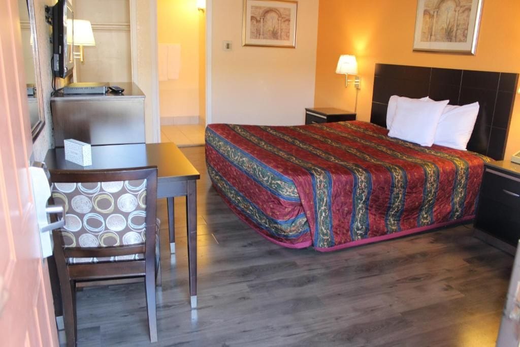 A hotel room with a bed, a desk, a chair, and a nightstand.