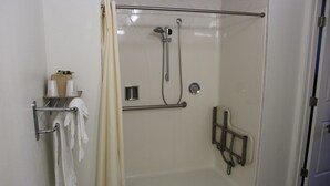 Un área de ducha con paredes de vidrio, un perchero, un cabezal de ducha y un panel de control.