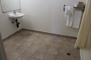 A bathroom with a sink, tiled floor, and a towel rack with towels. - Budget Inn Redwood City (Redwood City)