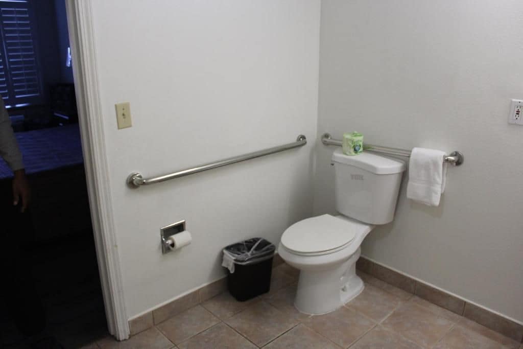 Une salle de bain standard équipée de toilettes, d’une barre d  ’appui et d’une poubelle.