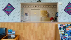 Zona de recepción con un mostrador de madera, un reloj y decoraciones en la pared con motivos.