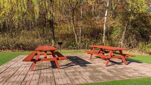 Two picnic tables on a brick patio with a grassy area and trees in the background. - SureStay Plus Hotel by Best Western Highland Poughkeepsie (Highland)