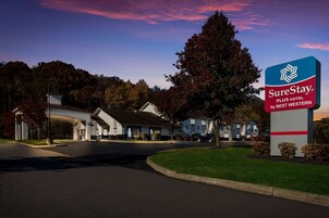 Un hotel SureStay Plus by Best Western con un letrero grande, un estacionamiento y una carretera que conduce a la entrada.