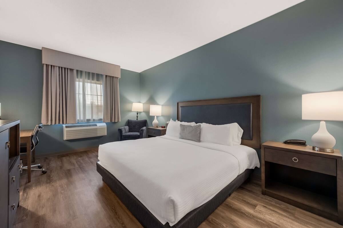 A hotel room with a large bed, bedside tables, a desk, and a chair.