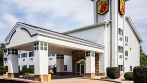 Un hôtel Super 8 doté d’un parking couvert, d’une façade en pierre et d’une enseigne « Super 8 » bien visible sur le bâtiment.