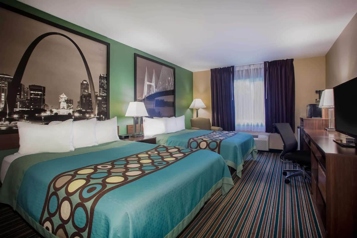 A hotel room with two beds, a desk, a TV, and a cityscape view.