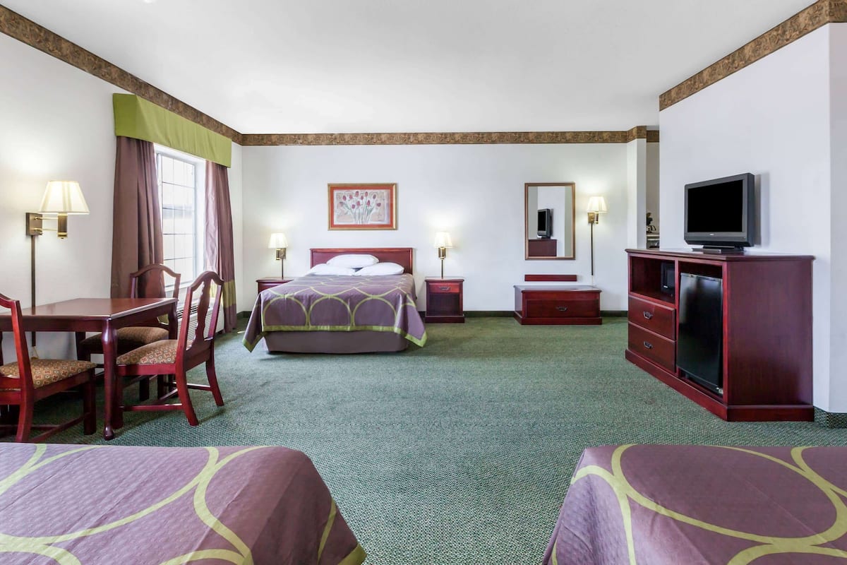 A hotel room with a bed, two bedside tables, a TV, a desk, and two chairs.