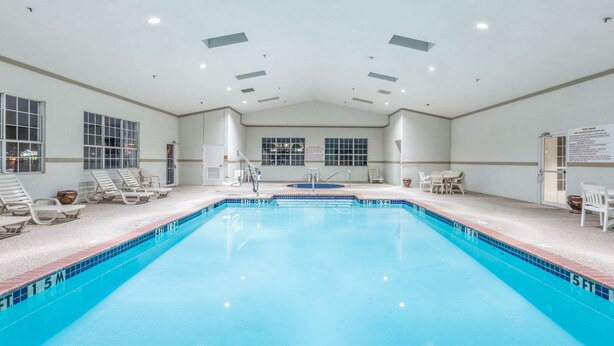 A large indoor swimming pool with clear water, surrounded by lounge chairs and a tiled deck.