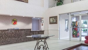 A lobby with a reception desk, a glass-top table, a red sofa, and a framed picture on the wall.