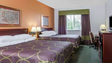 Quarto de hotel com duas camas, uma mesa, uma cadeira, televisão e obras de arte nas paredes.