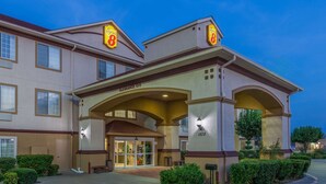 A hotel entrance with a clear sign, a covered entrance, and a well-lit facade.