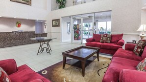 A lobby with a reception desk, red sofas, a coffee table, and a large window.