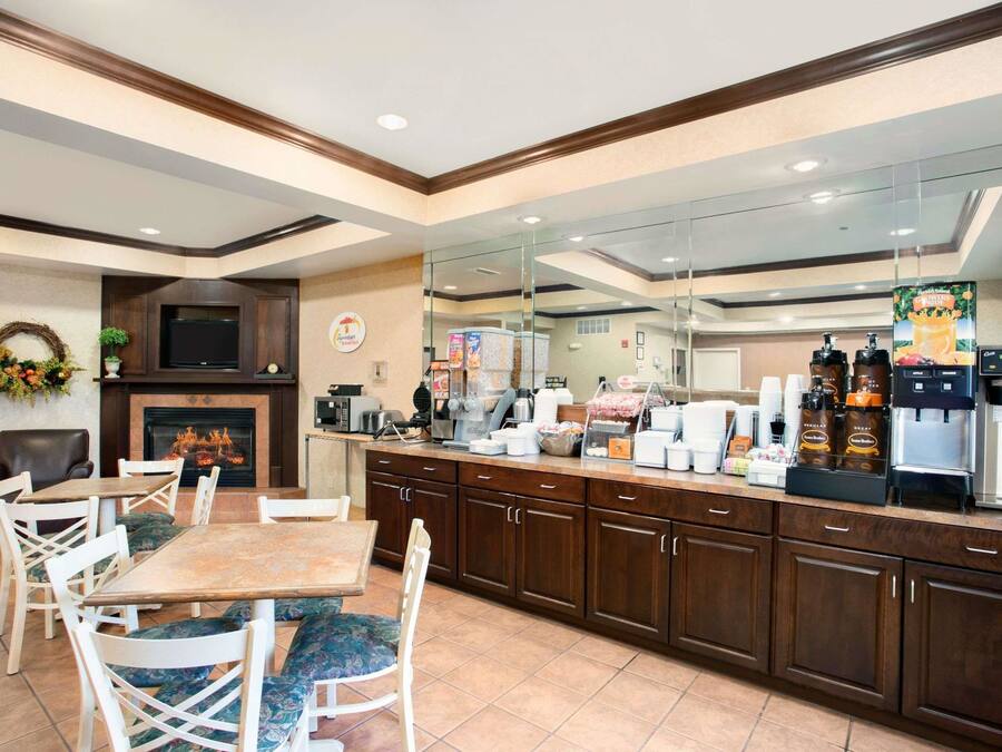 Un vestíbulo de hotel con zona de comedor, chimenea, televisor y estación de café.