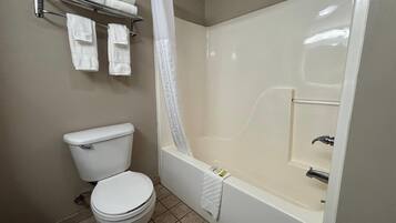 Un baño con inodoro, bañera y cortina de ducha.