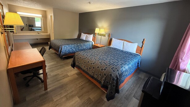 A hotel room with two beds, a desk, a chair, a mirror, and a TV.