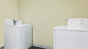 A laundry area with two white washing machines against a light yellow wall. - Super 8 by Wyndham Petersburg (Petersburg)