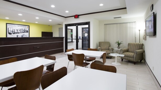 A modern hotel lobby with a reception desk, seating area, and a large poster on the wall. - Super 8 by Wyndham Petersburg (Petersburg)