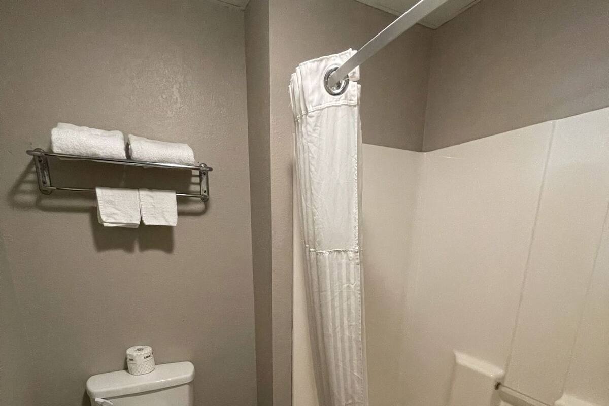 A bathroom with a toilet, a shower curtain, and a towel rack.