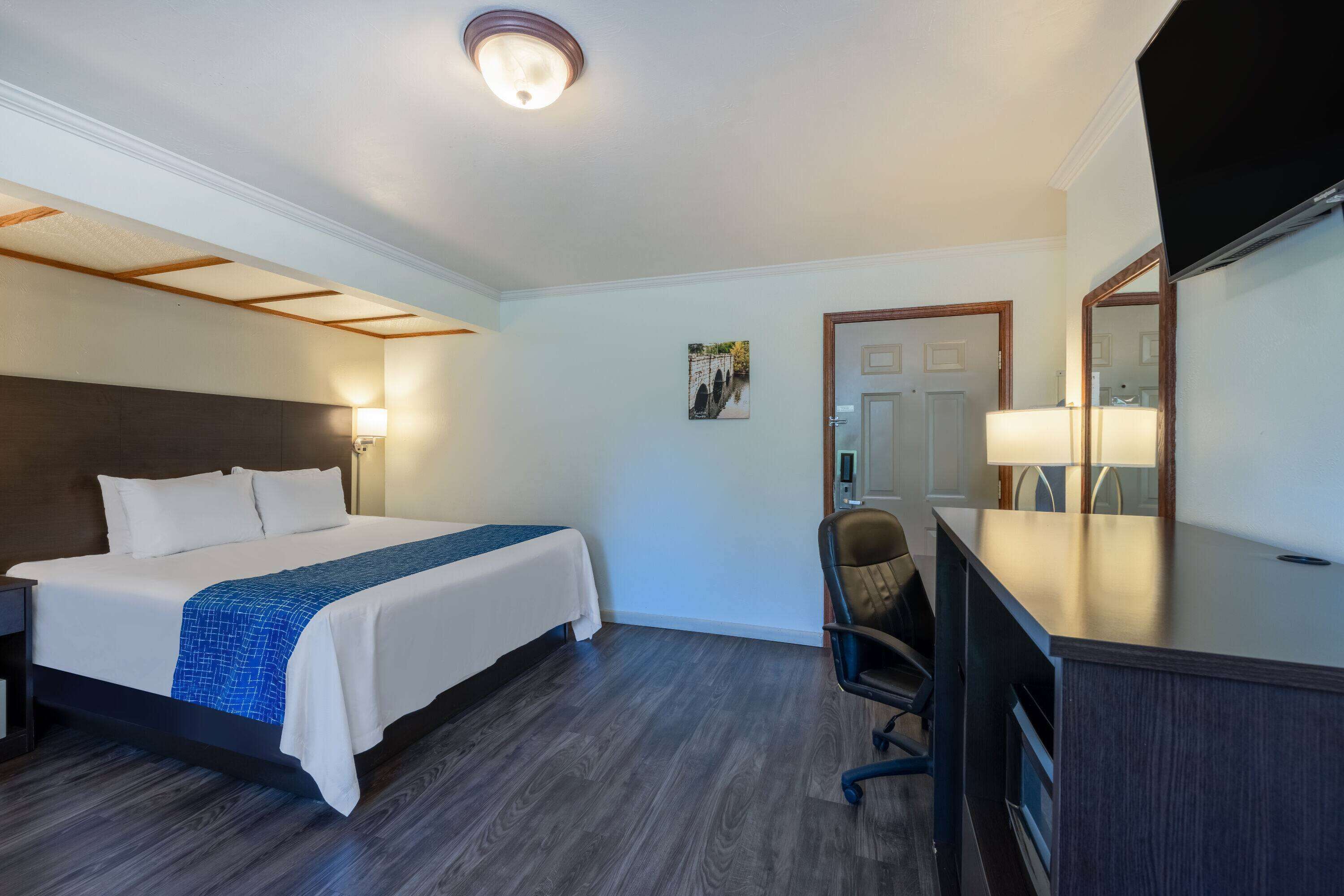 Une chambre d’hôtel équipée d’un lit, d’un bureau, d’une chaise et d’un téléviseur.