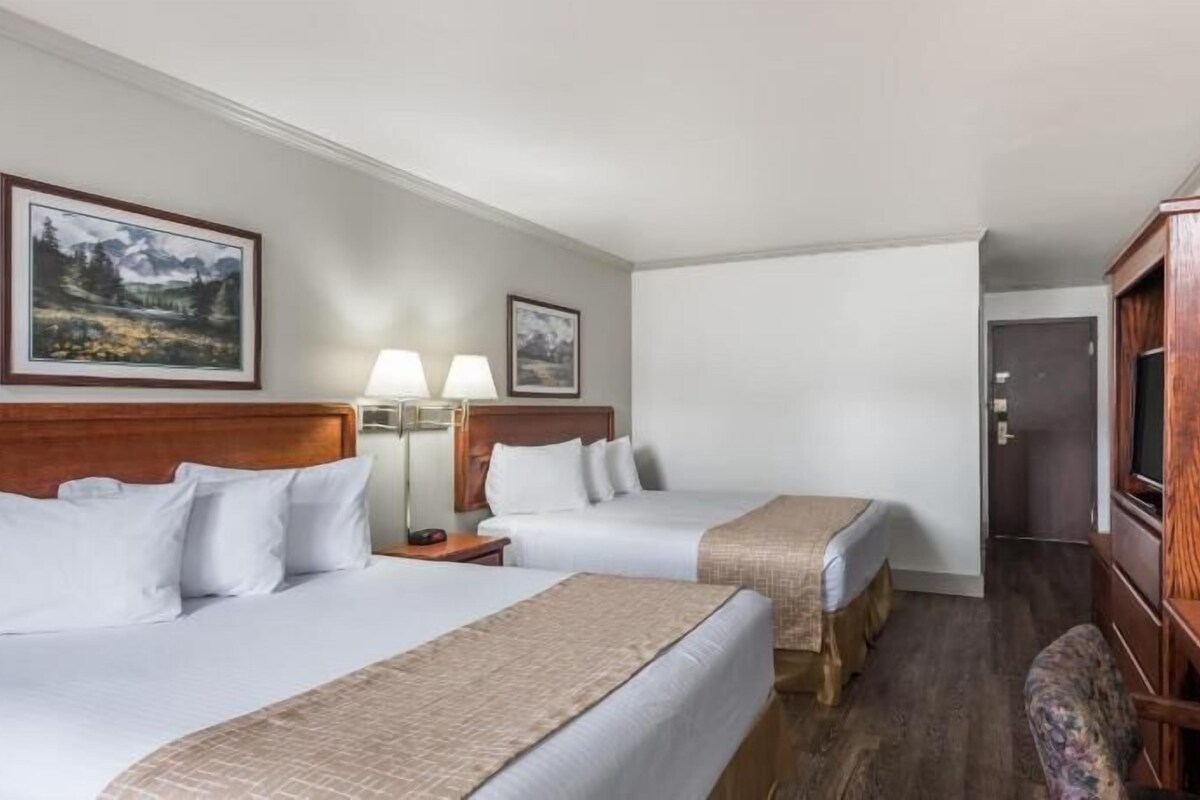 Een hotelkamer met twee bedden, een houten bureau, een televisie en twee wandlampen.