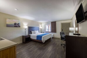 Ein Hotelzimmer mit Bett, Schreibtisch, Stuhl und Fernseher.