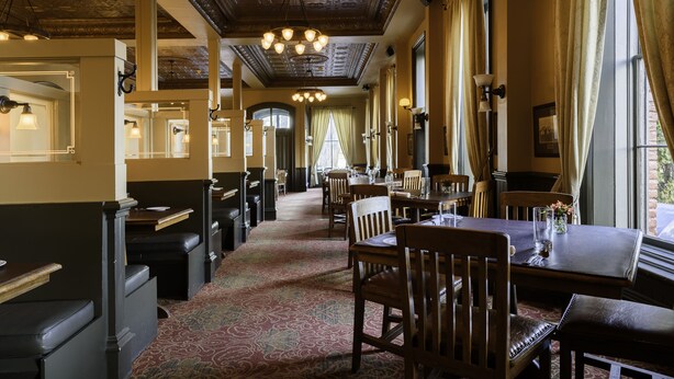 Ein Restaurant mit hohen Decken, aufwendigen Details an der Decke und einem gemusterten Teppich.