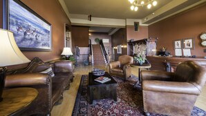 Eine Lobby mit Ledersofas, einem Couchtisch, einer Kristallleuchter, einer Treppe und einer Rezeption.